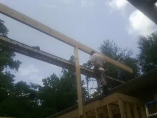 Carpenter setting a ridge beam over a new addition frame — Ice Dam Removal by Roofing Brothers in Dannemora