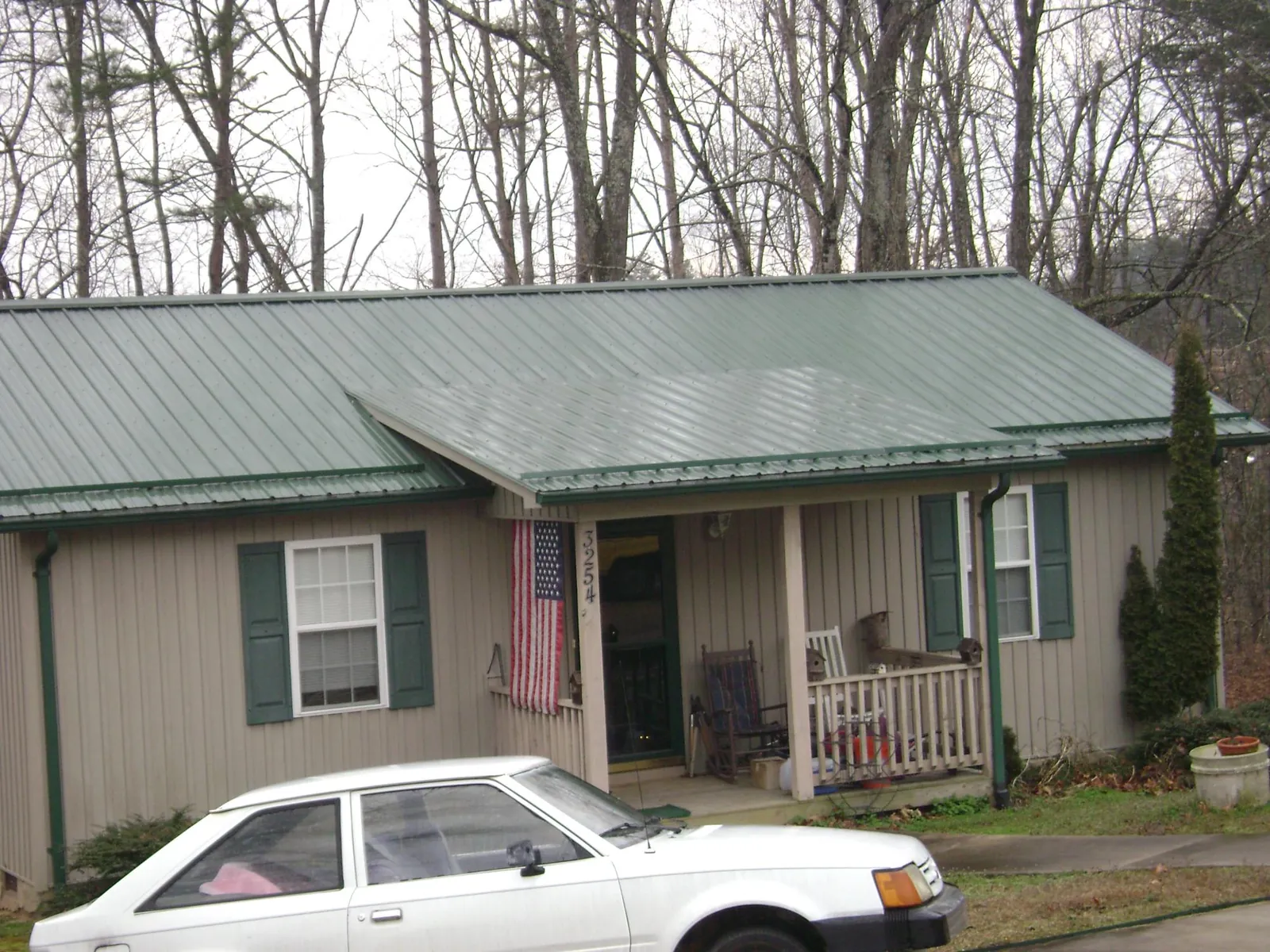 Green metal roof and front porch on a tan sided cottage in Dannemora