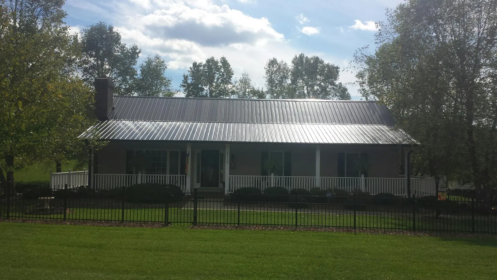 Gray metal roof on a brick ranch with a full width front porch — Gutter Guard Installation work by our crew in Dannemora