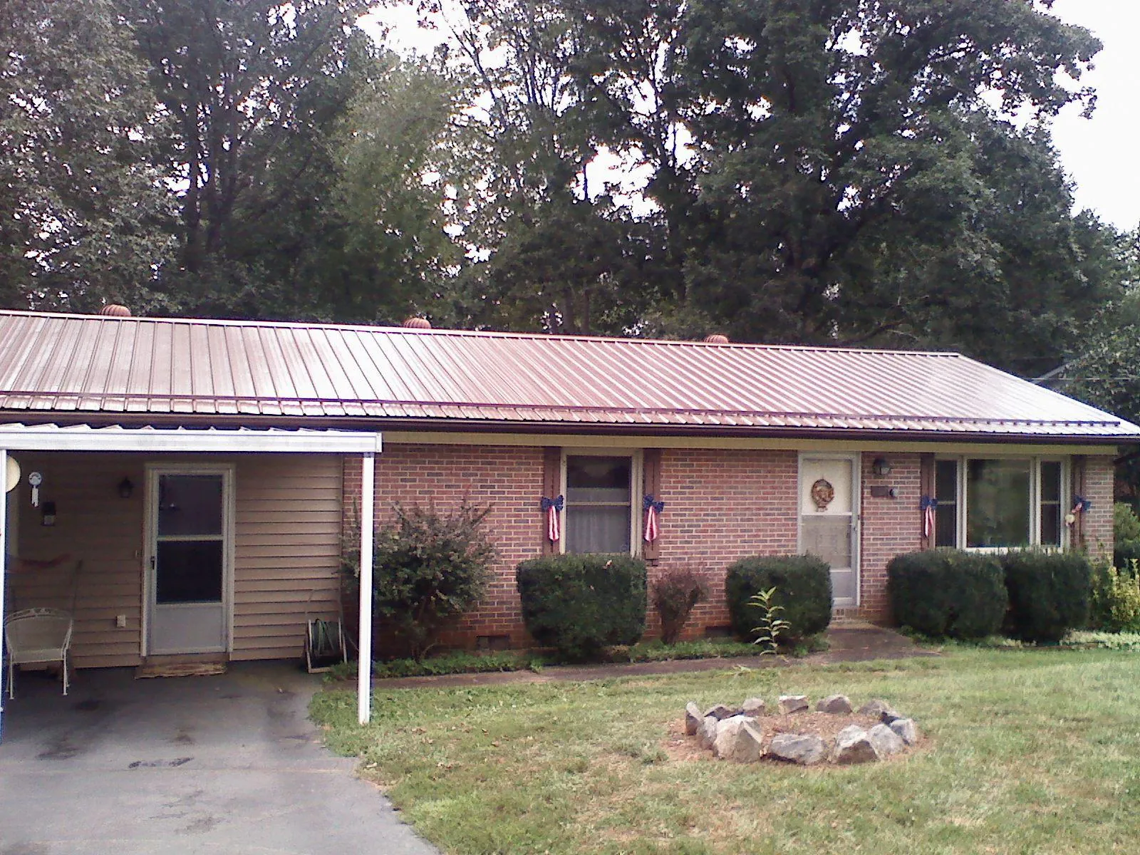 Bronze metal roof and carport on a brick ranch home — Roof Repair work by our crew in Dannemora