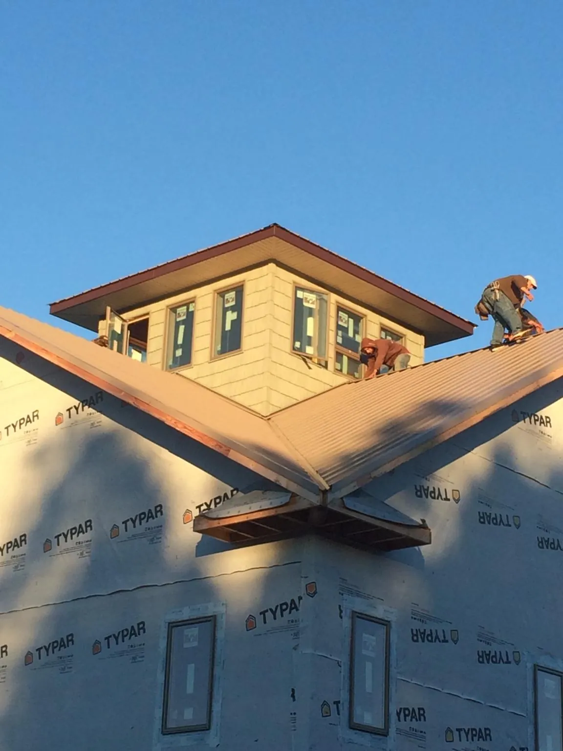 Roofers working around a rooftop cupola on a new metal roof at sunset — Roof Waterproofing in Dannemora by Roofing Brothers